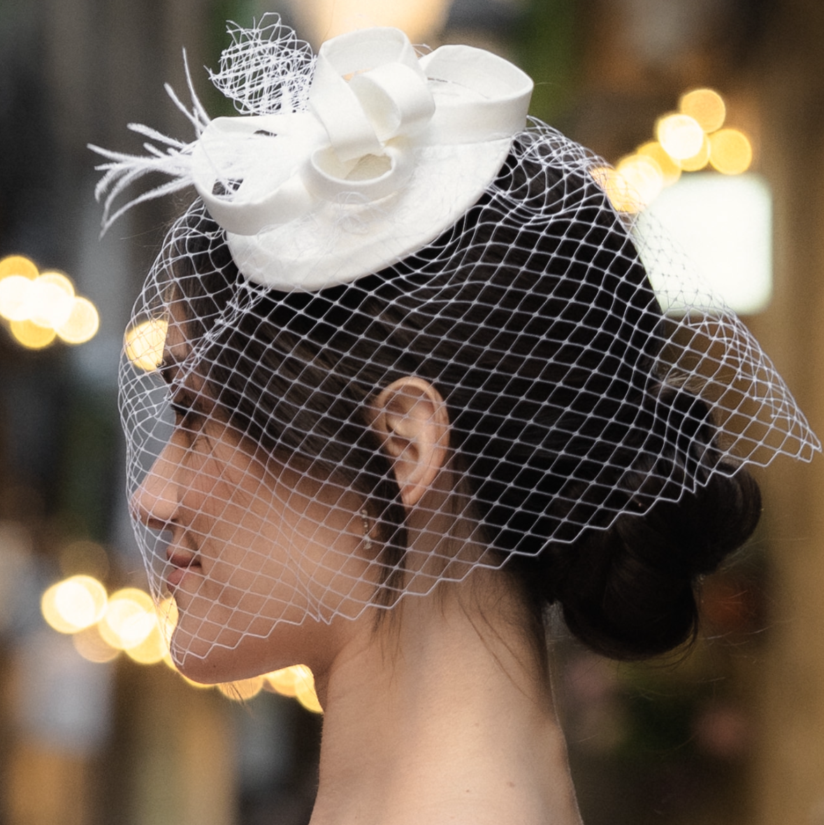 Ivory birdcage veil bridal headpiece with bow detail, styled in a classic updo
